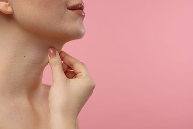 Photo of Woman touching her neck on pink background, closeup. Space for text