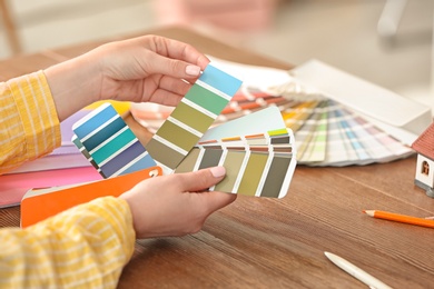 Female designer working with color palette samples at table