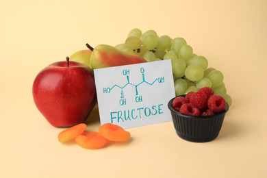 Photo of Card with word Fructose, delicious ripe fruits, raspberries and dried apricots on beige background