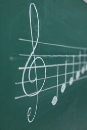 Photo of Musical notes written with chalk on green board, closeup