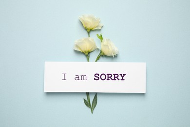 Image of Apology. White card with phrase I Am Sorry and beautiful Eustoma flowers on light mint color background, flat lay