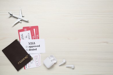 Flat lay composition with passport, toy plane and tickets on white wooden background, space for text. Visa receiving