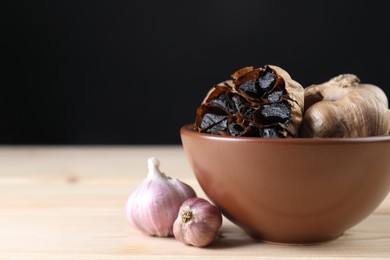 Photo of Fresh and fermented black garlic on wooden table
