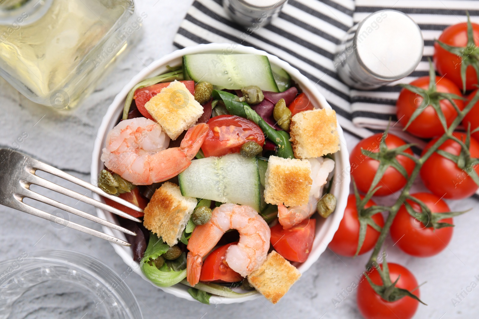 Photo of Tasty salad with croutons, tomato and capers on white textured table, flat lay