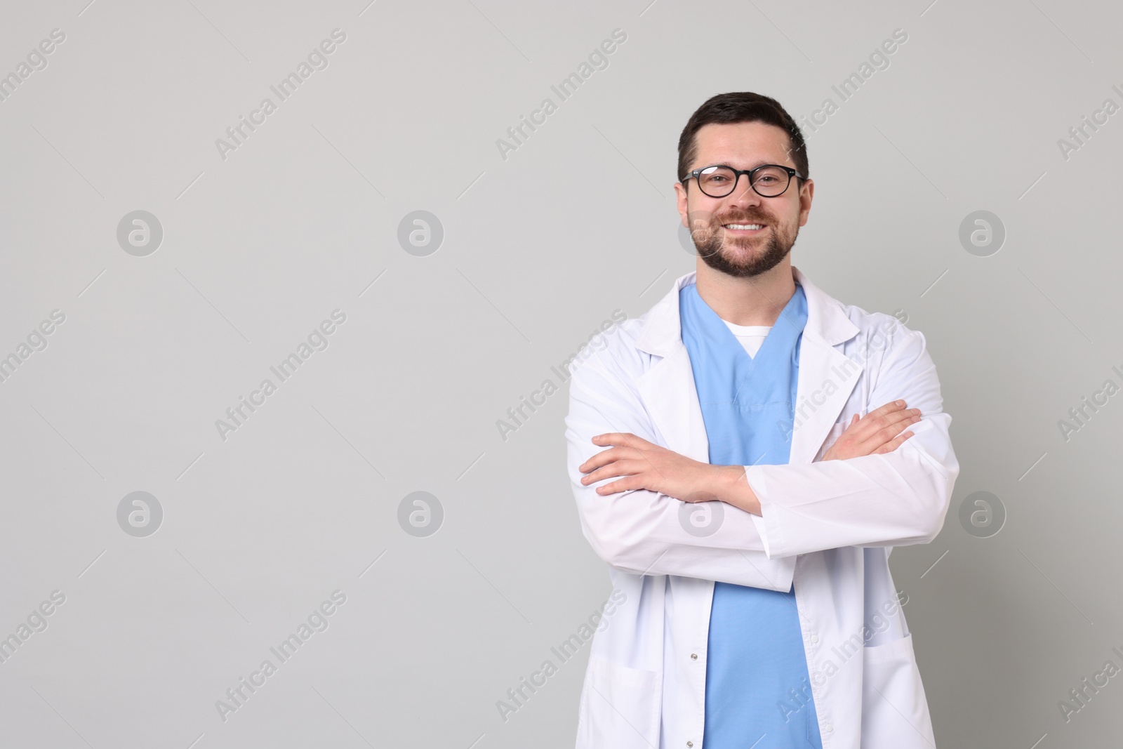 Photo of Portrait of smiling doctor on light grey background. Space for text
