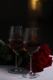 Photo of Glasses of red wine and rose flowers on white table. Romantic atmosphere