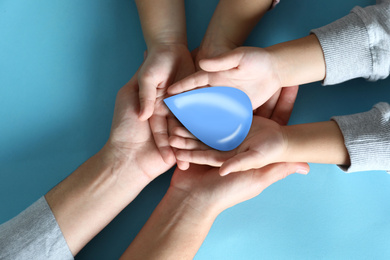 Image of Family holding water drop on blue background, top view. Ecology protection