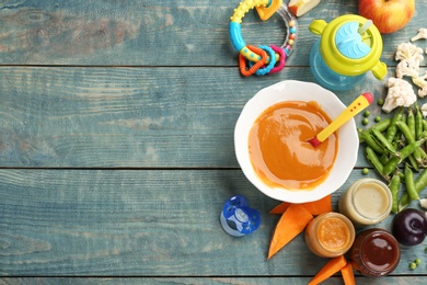 Plate with healthy baby food and ingredients on wooden table, top view