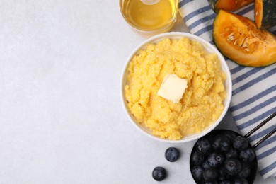 Photo of Tasty cornmeal with butter in bowl and products on light gray table, flat lay. Space for text