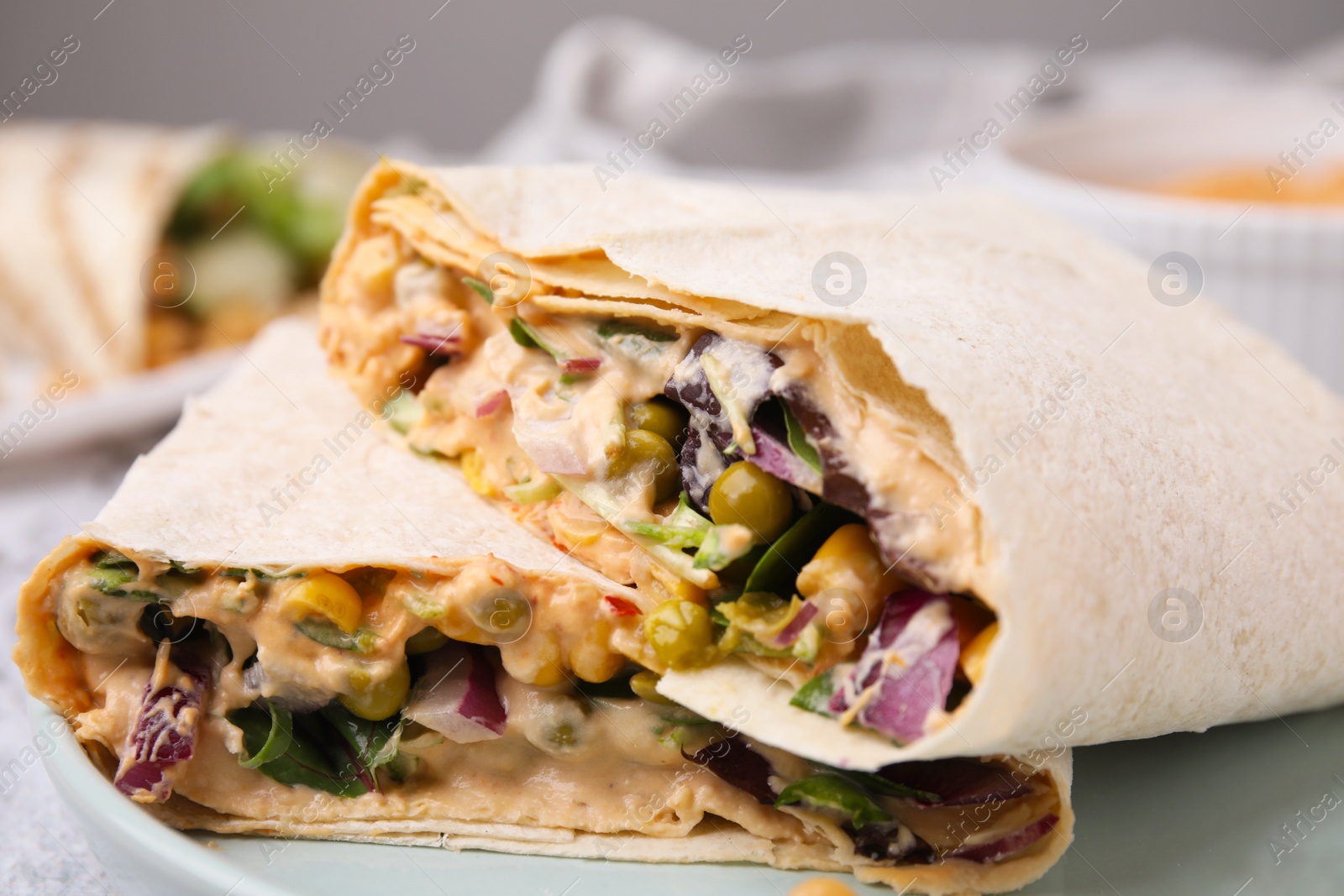 Photo of Delicious hummus wraps with vegetables, closeup view