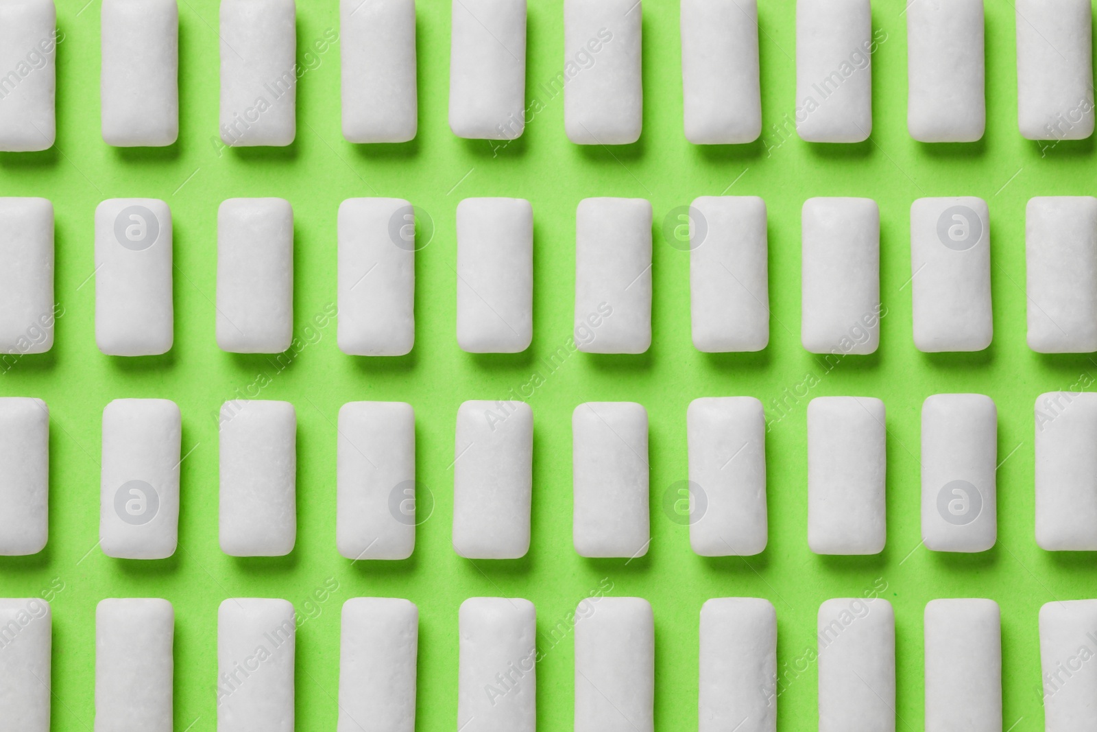 Photo of Many chewing gum pieces on green background, flat lay