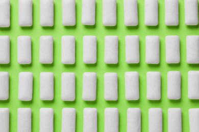 Photo of Many chewing gum pieces on green background, flat lay