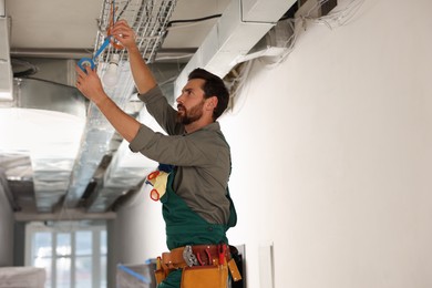 Photo of Electrician with insulting tape repairing ceiling lamp