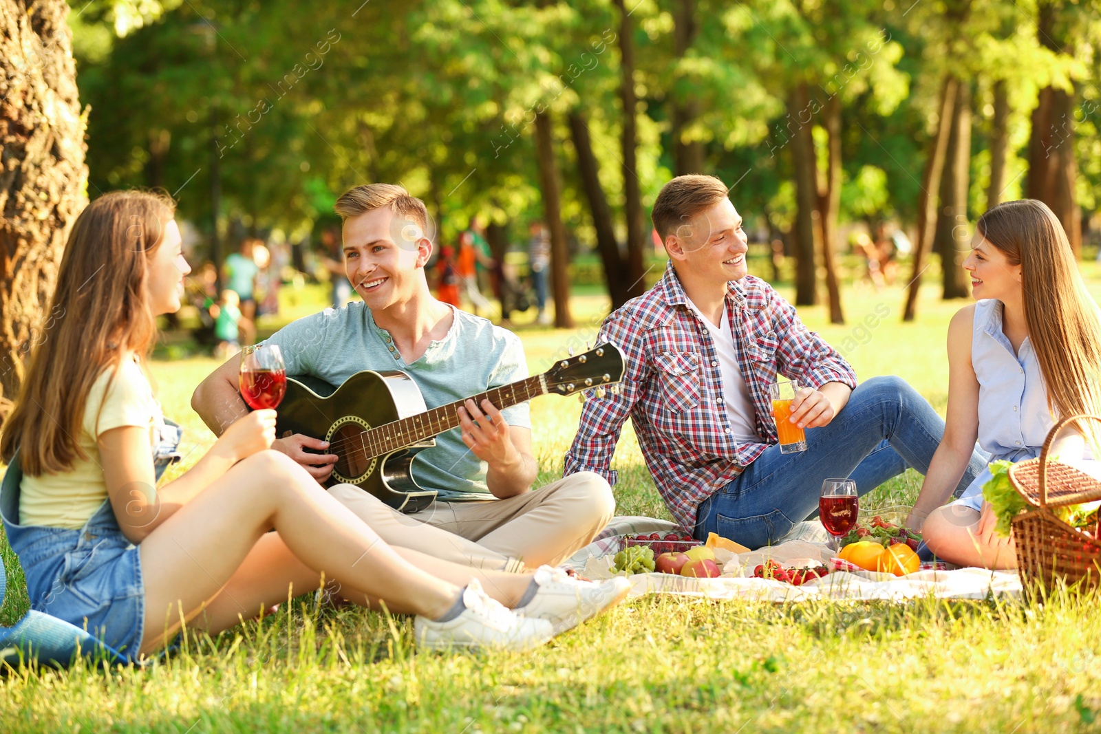 Photo of Young people enjoying picnic in park on summer day