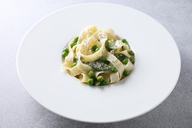 Delicious pasta with green peas on grey table