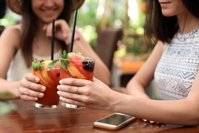 Women with glasses of tasty lemonade at table, closeup