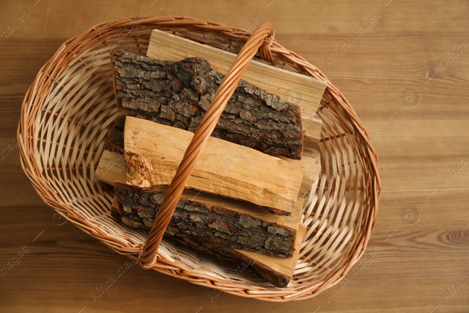 Photo of Wicker basket with firewood on floor indoors, top view