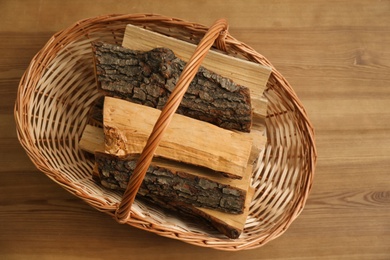 Photo of Wicker basket with firewood on floor indoors, top view