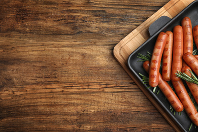 Photo of Delicious grilled sausages on wooden table, top view. Space for text