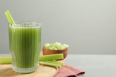 Photo of Glass of delicious celery juice and vegetables on grey table, closeup. Space for text