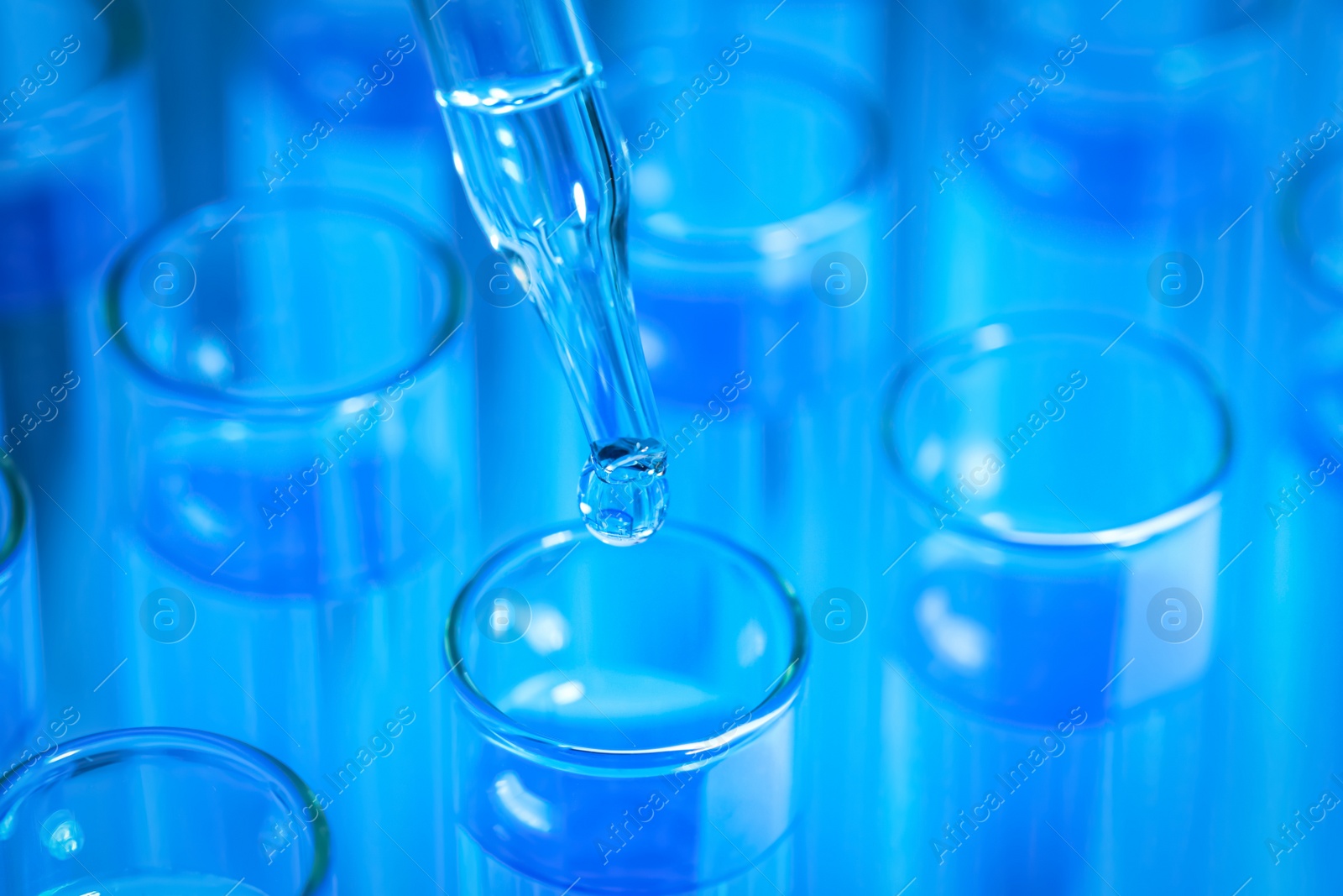 Photo of Dripping reagent into test tube with blue liquid, closeup. Laboratory analysis