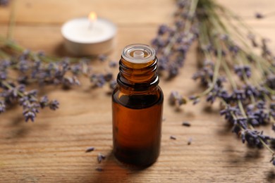 Photo of Bottle of essential oil and lavender flowers on wooden table