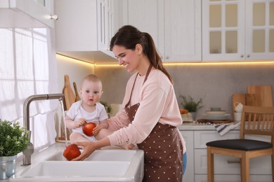 Mother and her cute little baby spending time together in kitchen, space for text
