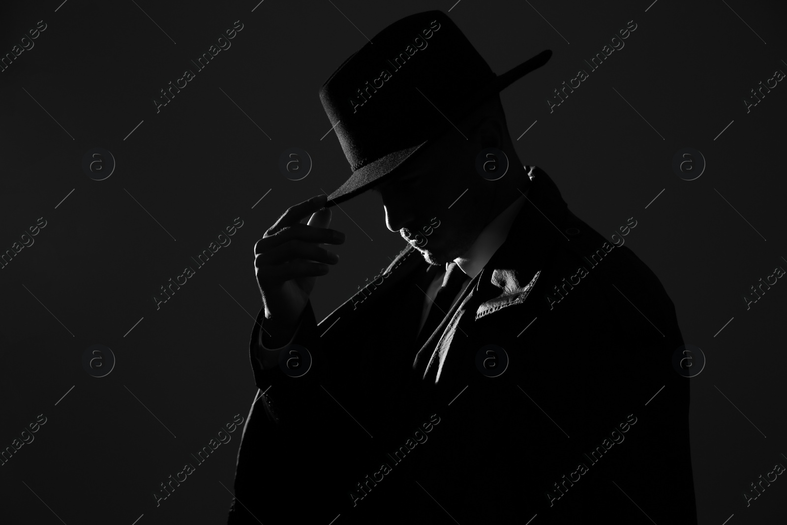 Photo of Old fashioned detective in hat on dark background, black and white effect