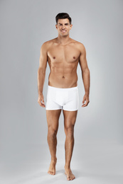 Handsome man in white underwear on light grey background