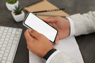 Photo of Man holding mobile phone with empty screen at table, closeup