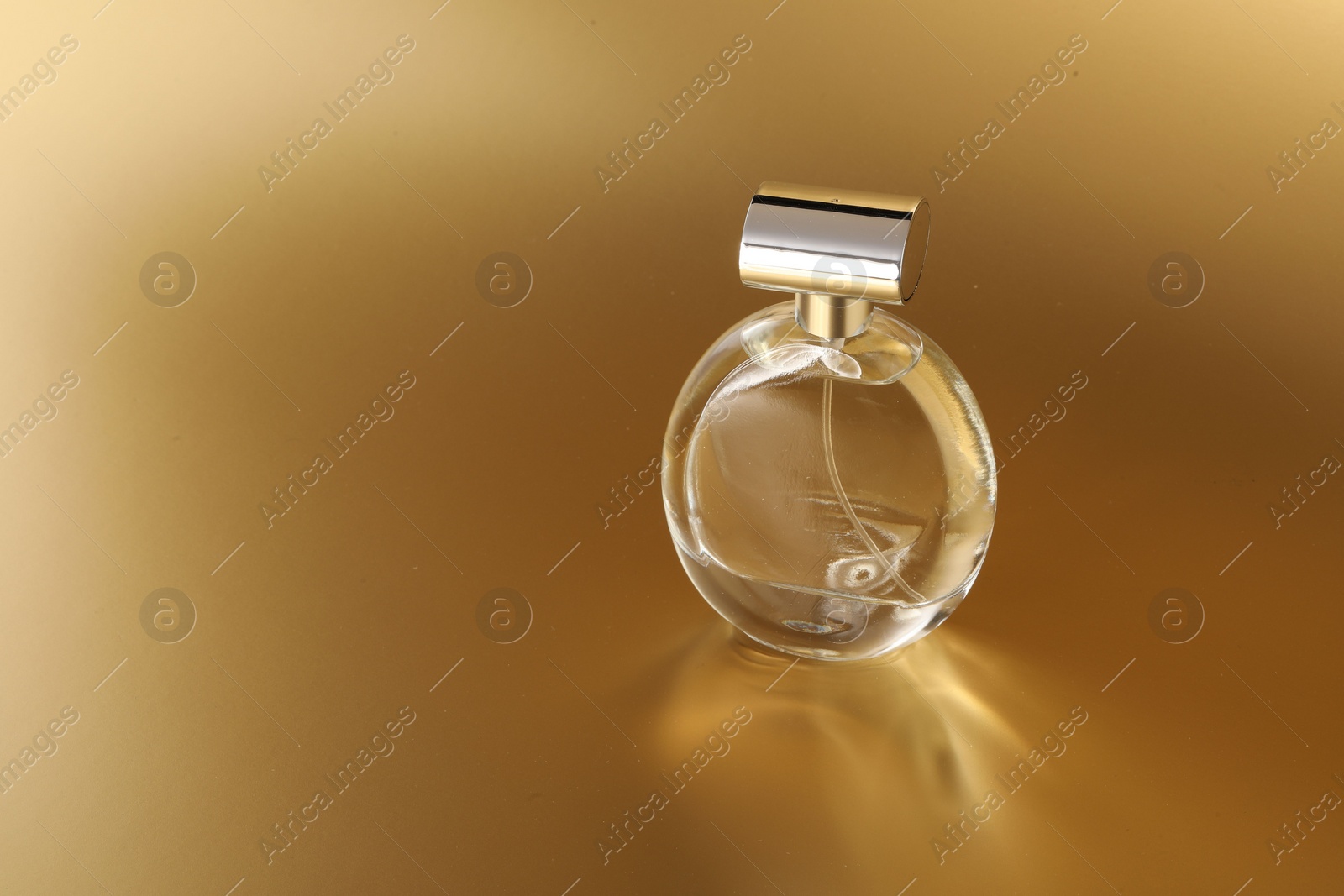 Photo of Luxury women's perfume. Sunlit glass bottle on golden background, space for text