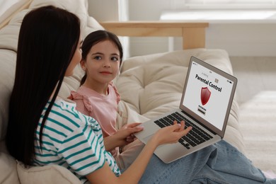 Mom installing parental control on laptop at home. Child safety