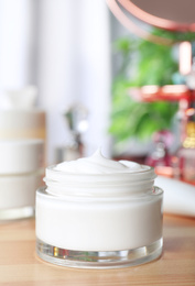Photo of Open jar of cream on wooden dressing table