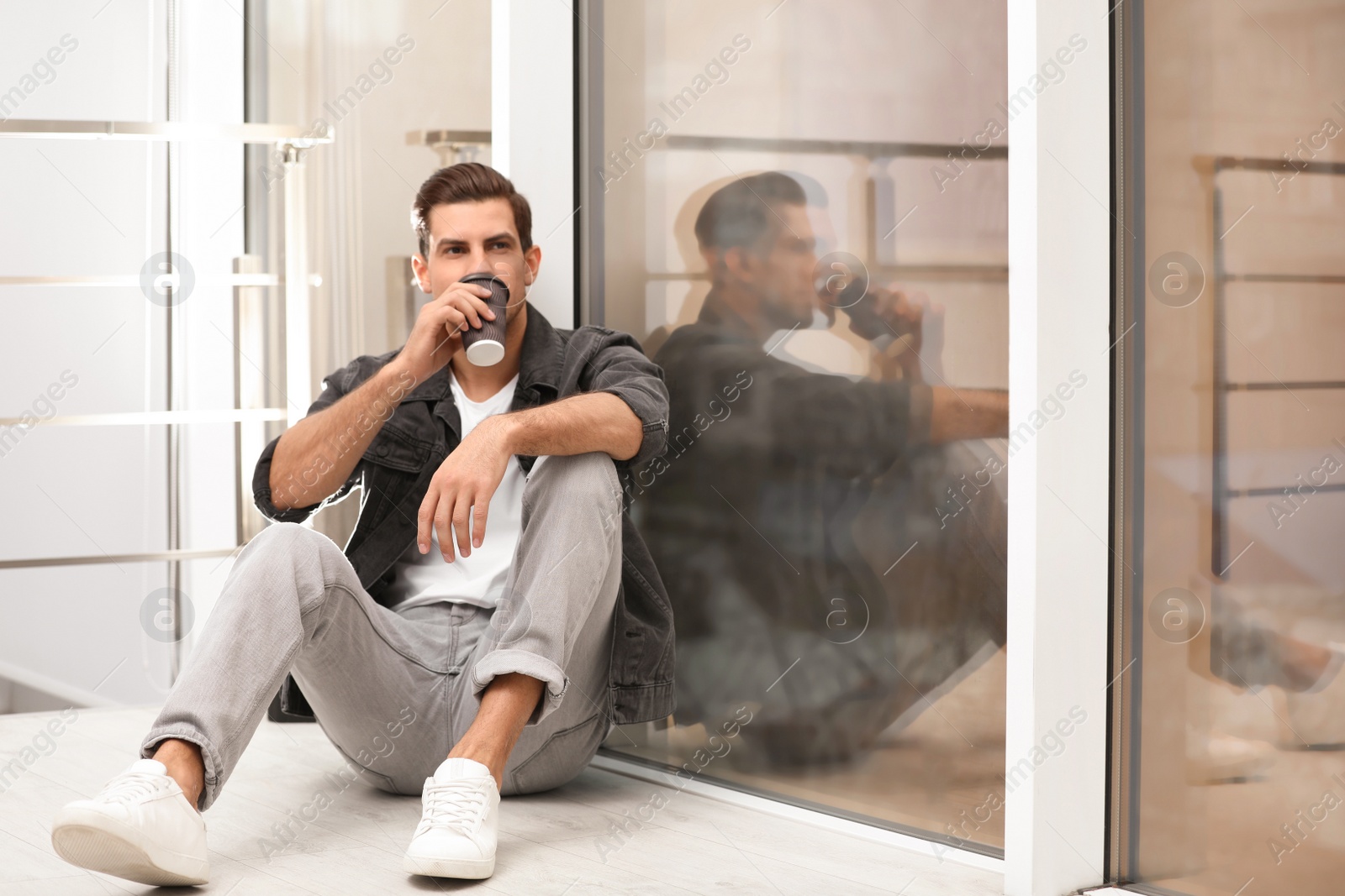 Photo of Handsome man drinking coffee near window at home