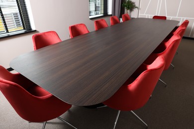 Photo of Empty conference room with stylish red office chairs and large wooden table