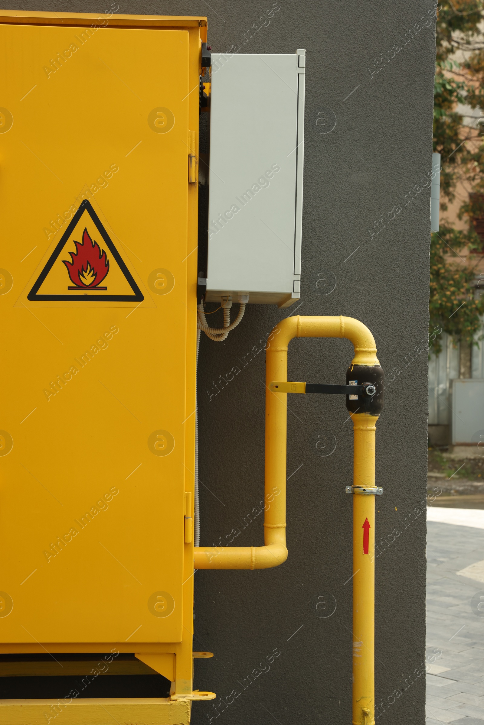 Photo of Yellow gas distribution cabinet near brown wall outdoors