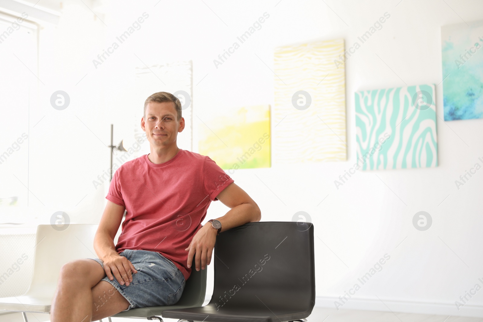Photo of Young man sitting on chair at exhibition in art gallery
