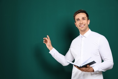 Photo of Portrait of male teacher with book on color background. Space for text