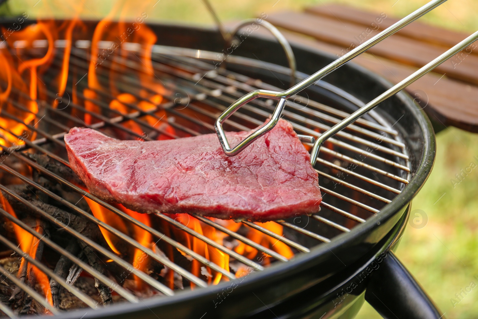 Photo of Tasty meat on barbecue grill with fire flames outdoors, closeup