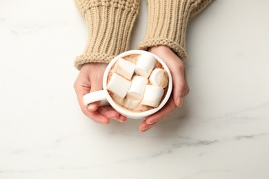 Photo of Woman with cup of tasty hot chocolate and marshmallows at white marble table, top view