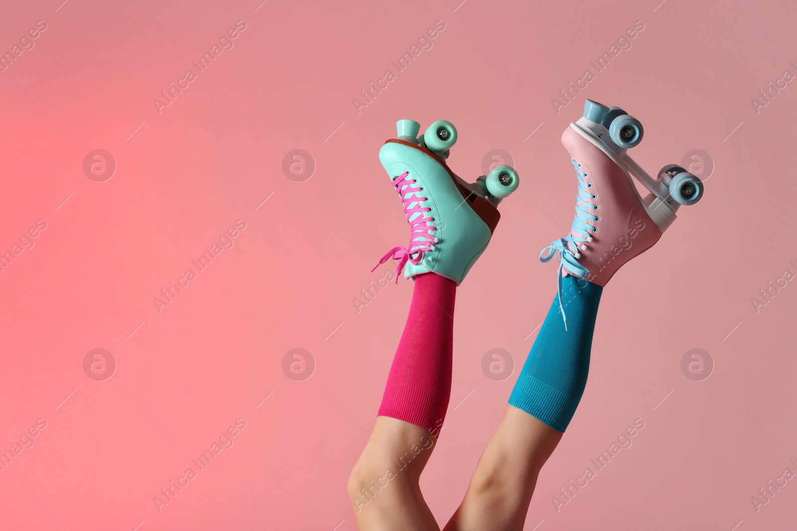 Photo of Woman with vintage roller skates on color background, closeup. Space for text