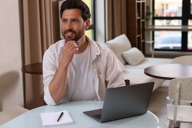 Man with laptop at table in cafe