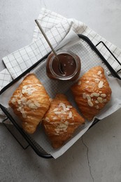 Delicious croissants with almond flakes and chocolate paste on light grey table, top view