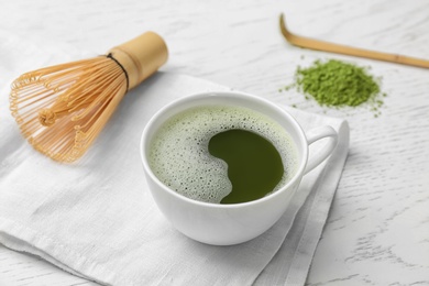 Photo of Cup of fresh matcha tea and chasen on table