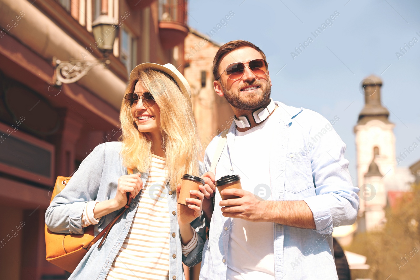 Photo of Happy couple with coffee on city street in morning