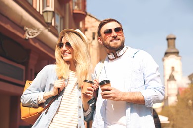 Happy couple with coffee on city street in morning