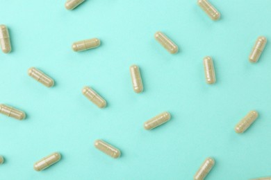 Photo of Many vitamin capsules on turquoise background, flat lay