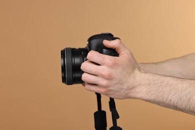 Photo of Photographer holding camera on beige background, closeup. Space for text