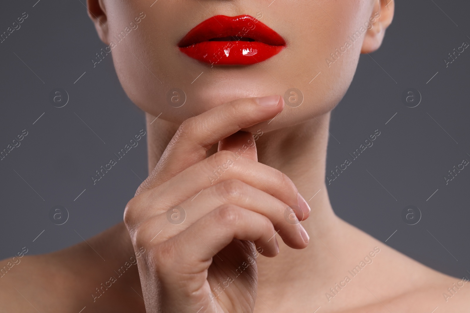 Photo of Young woman with beautiful red lips on grey background, closeup