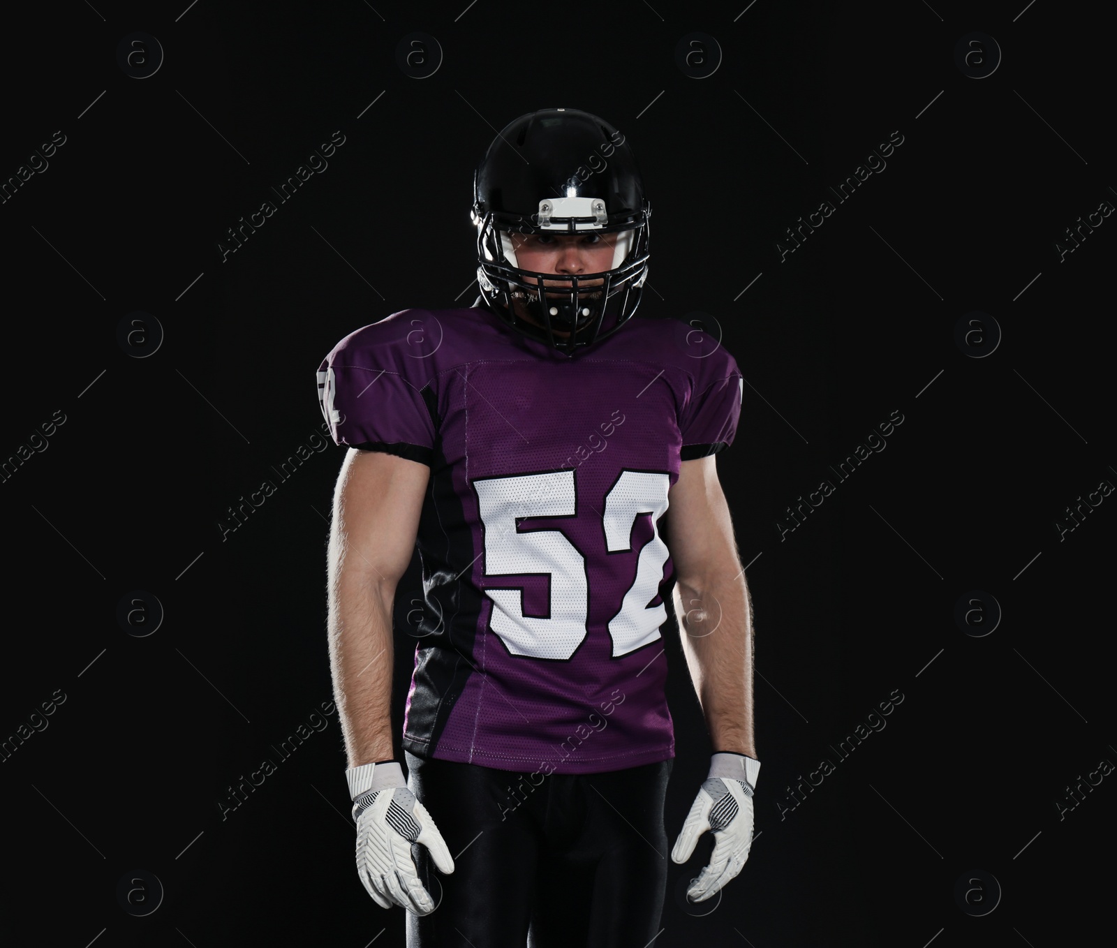 Photo of American football player wearing uniform on dark background